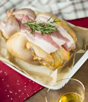 Tacchina Minor farcita cruda con pancetta e rosmarino in pirofila su tavolo